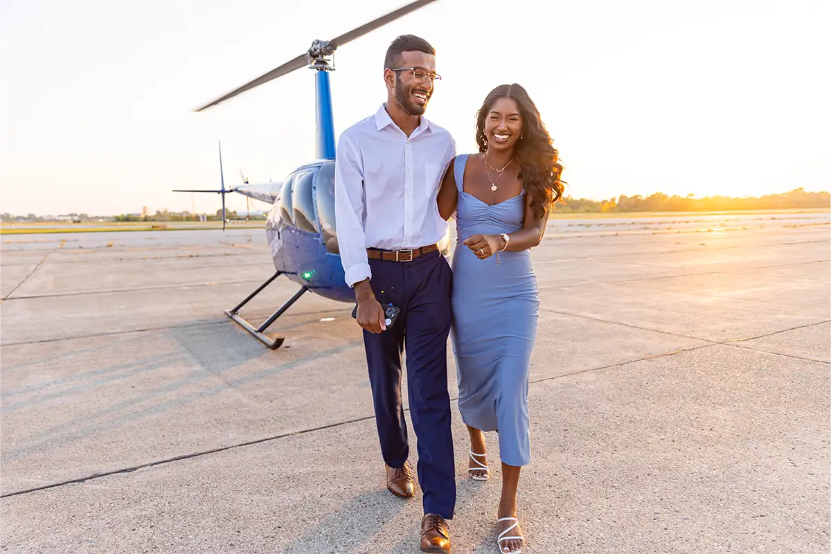 a sunset photo of a couple in front of a helicopter laughing in detroit