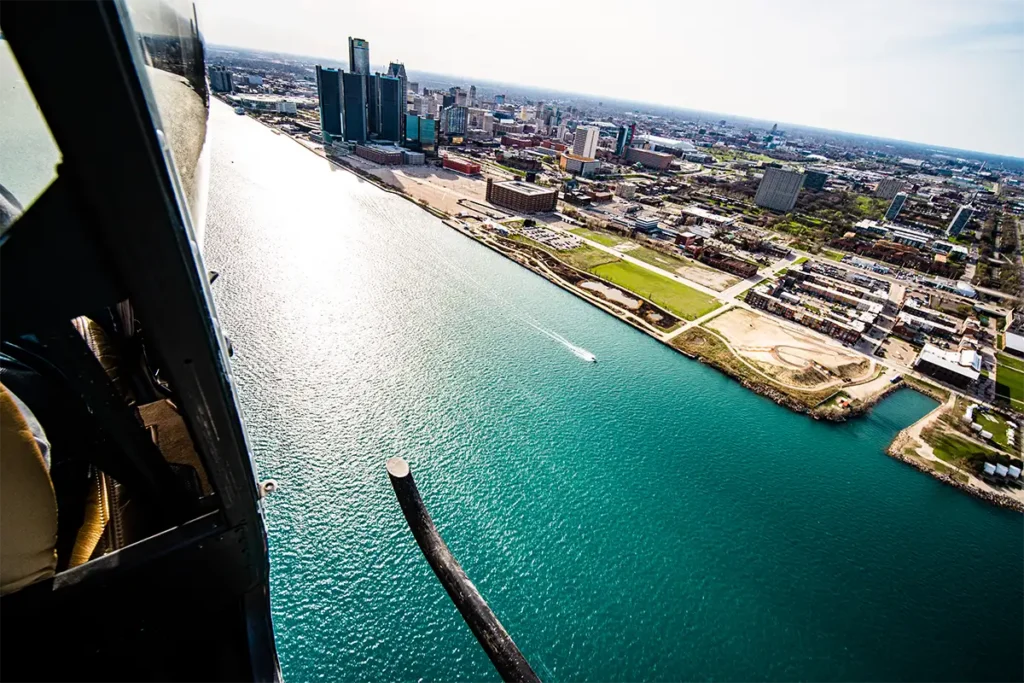 a helicopter low flying over the detroit river with no doors on a tour from myflight tours