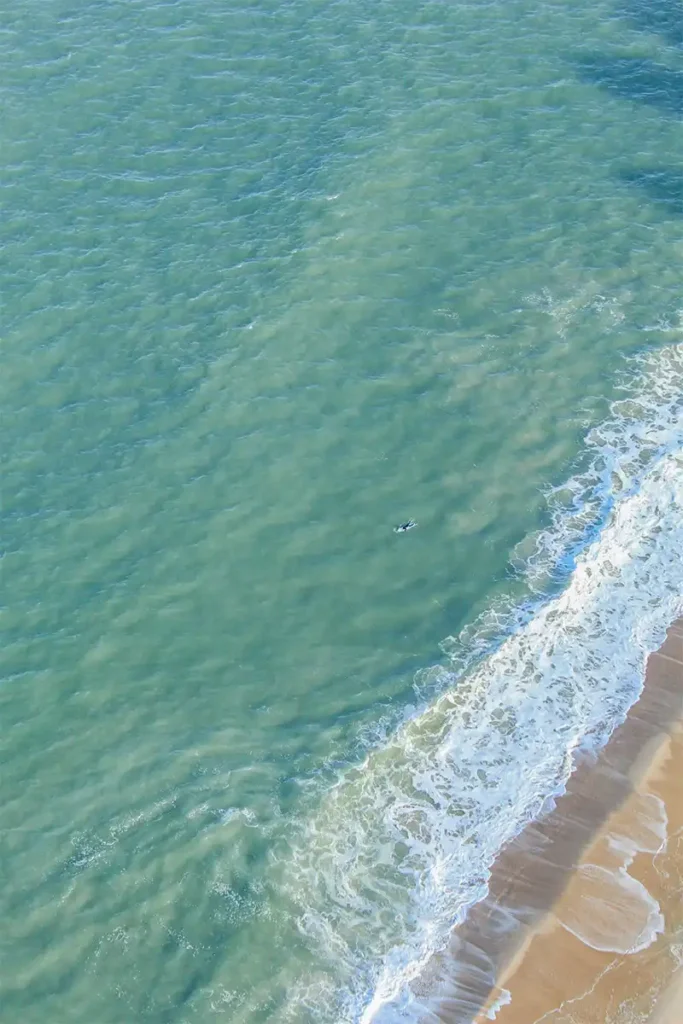 A top down view of a surfer in the Atlantic ocean along the coast of Ocean City, Maryland taken from a helicopter